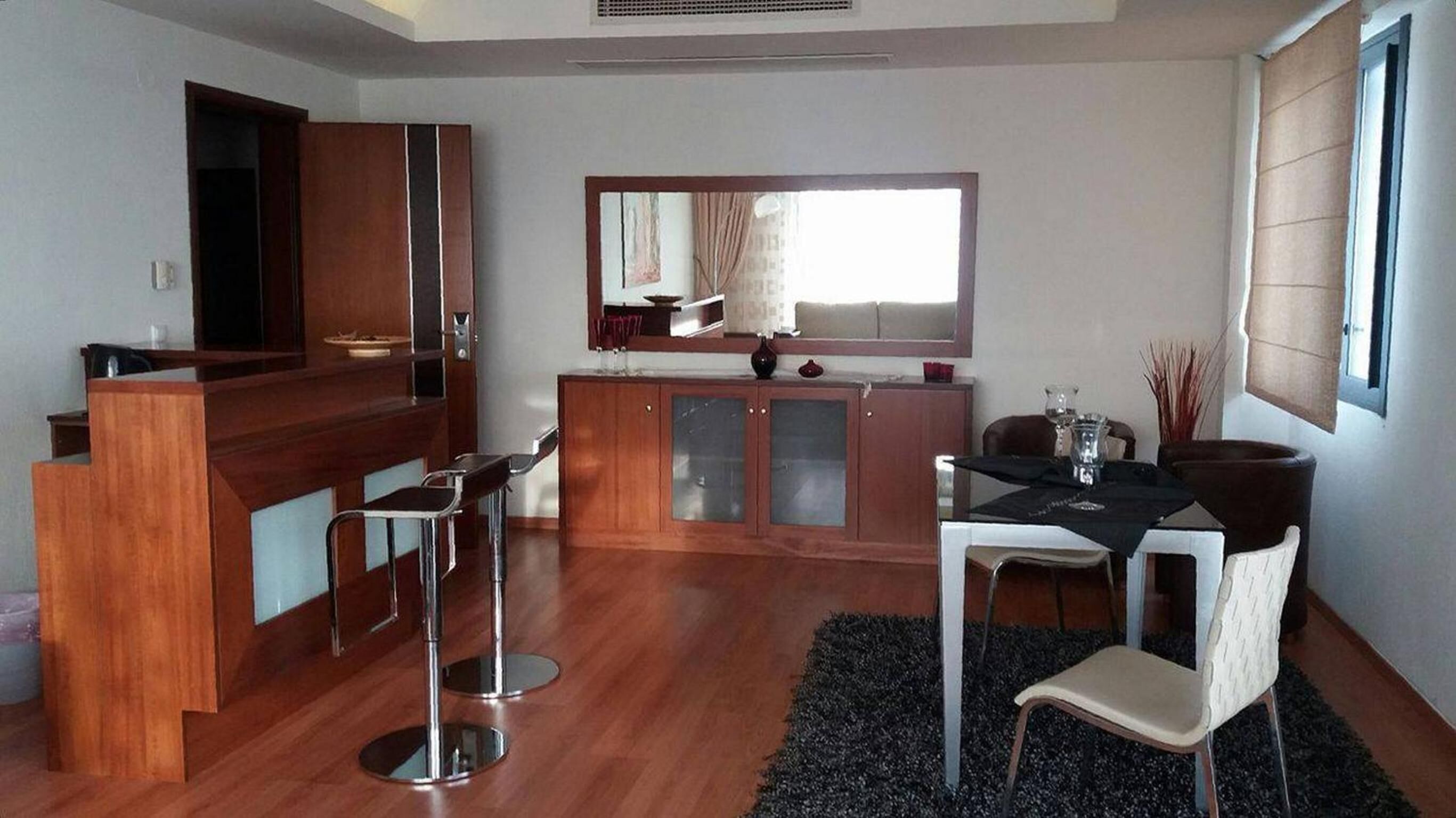 A modern kitchen with a dining area, wooden cabinets, and a large window.