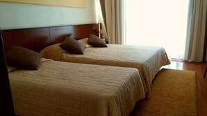 Two single beds with headboards, a wooden floor, and a beige carpet.
