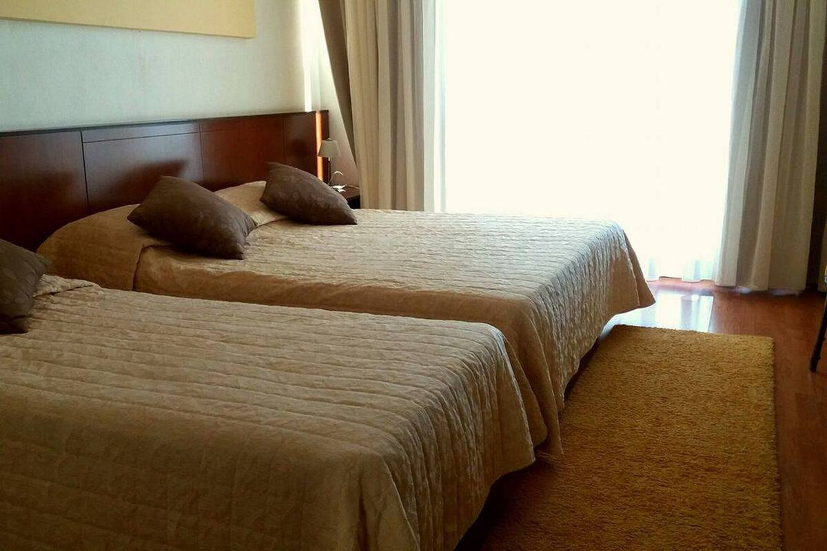 Two single beds with headboards, a wooden floor, and a beige carpet.