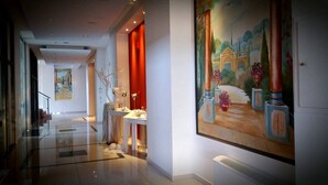 A modern hotel corridor with a large mural, a reception desk, and a staircase.