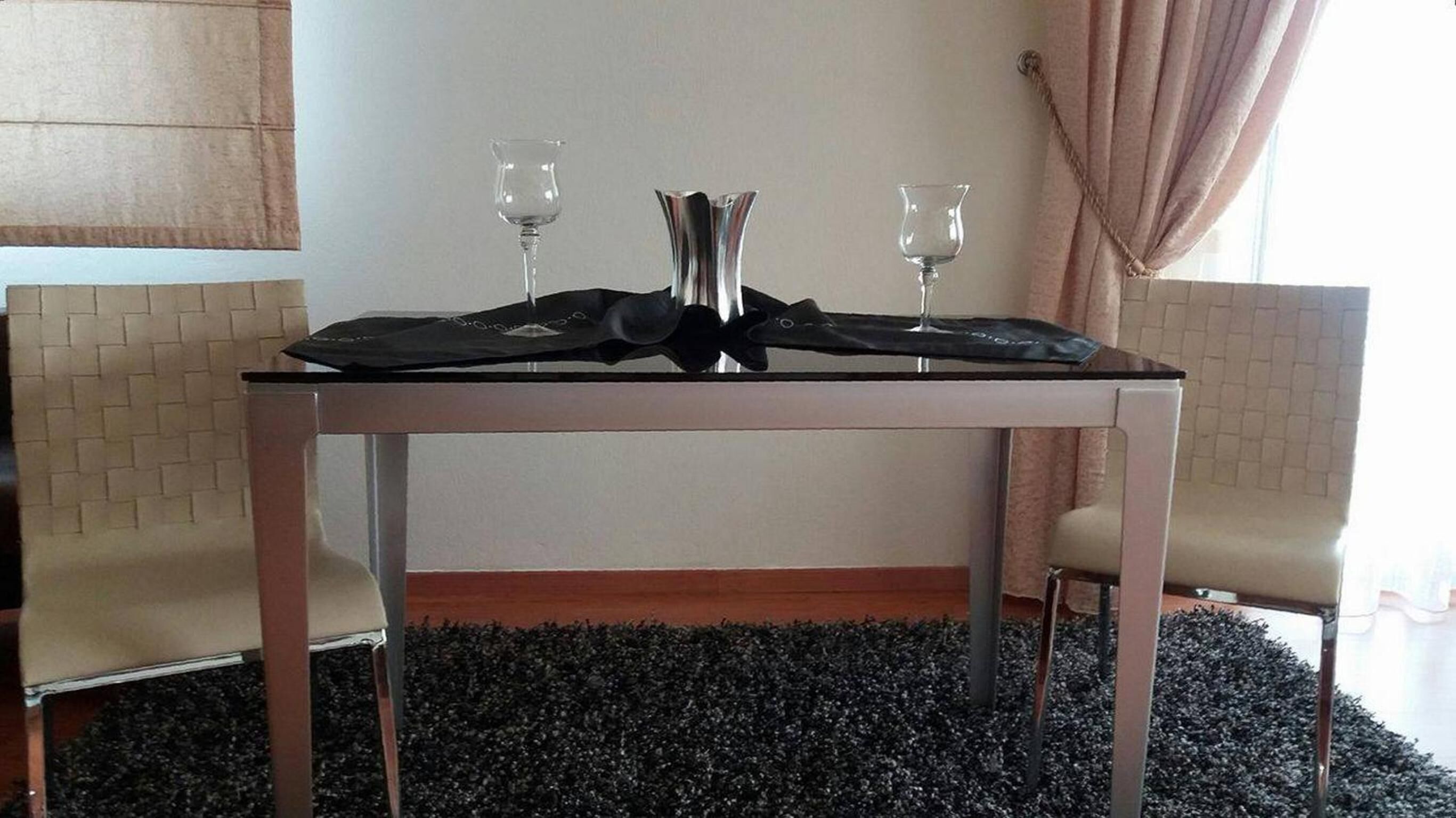 Une table à manger avec deux chaises, une nappe noire et deux verres à vin.