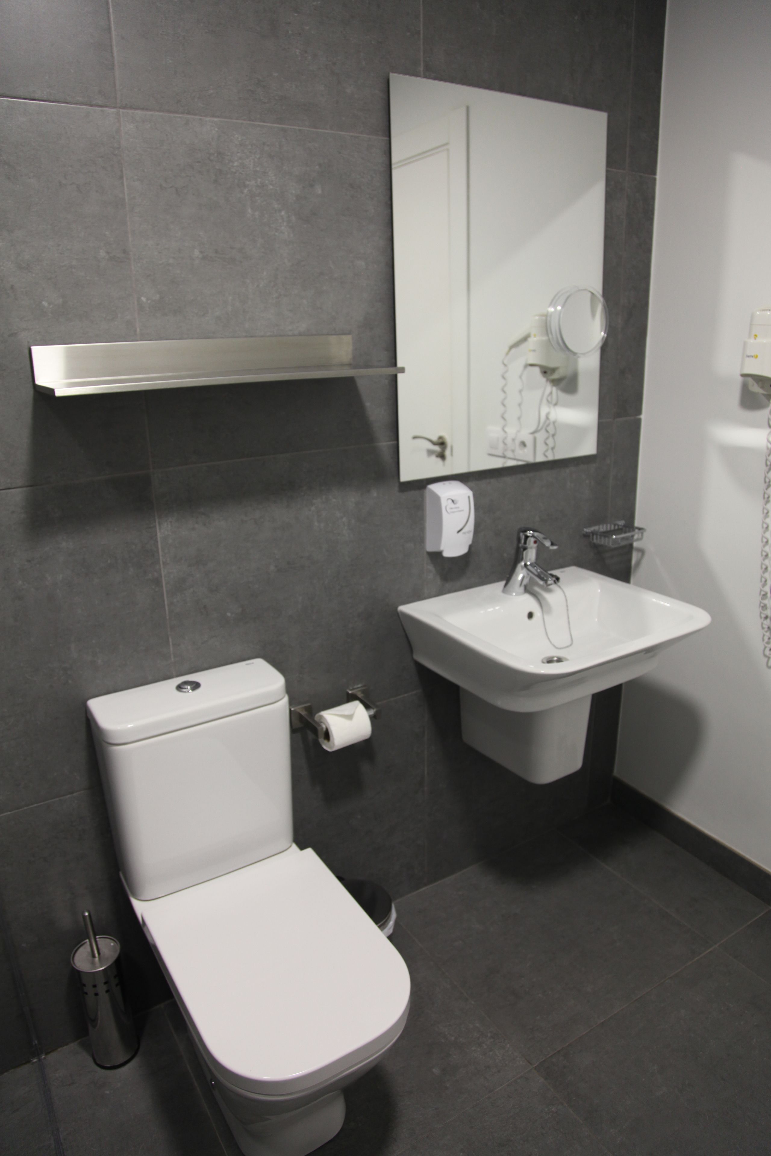 A modern bathroom with a toilet, sink, and mirror.