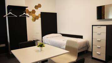 A hotel room with a bed, a desk, a chair, a dresser, and a wall-mounted TV.