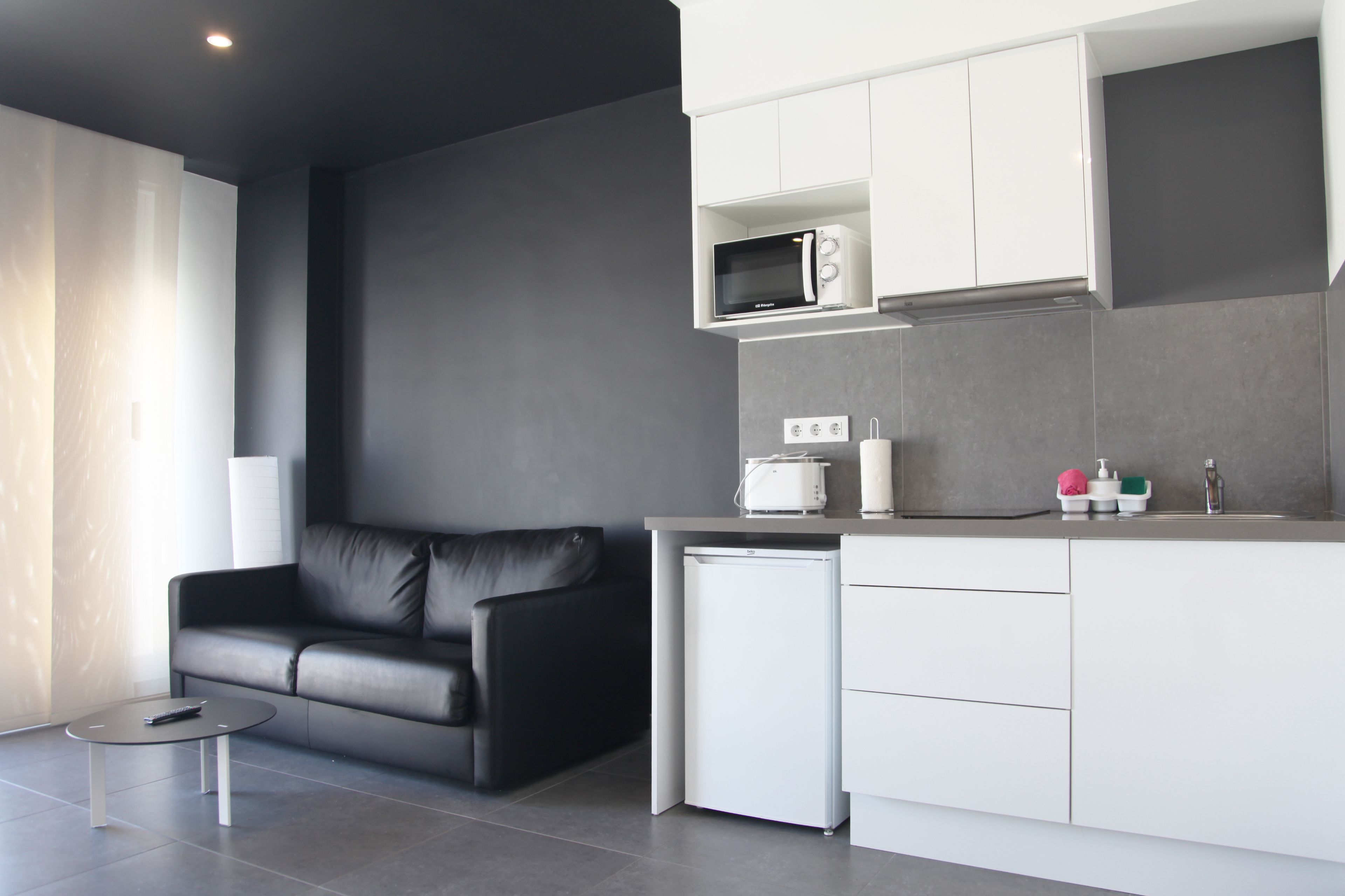 A modern kitchen with white cabinets, a built-in microwave, and a small refrigerator.