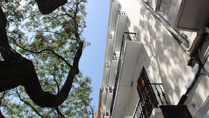 Un edificio con un letrero de SoHotel Valencia, un árbol en primer plano y un cielo despejado.