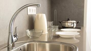 Una cocina moderna con un lavamanos de acero inoxidable, un florero blanco y una olla sobre la encimera.