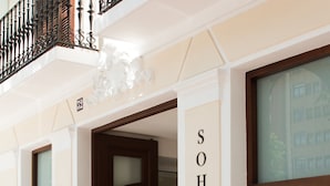 Entrada de un hotel con un letrero grande que dice "SOHOTEL" y una puerta de "AUTO-CHECKIN".