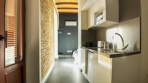 Una cocina estrecha con pared de ladrillo, un lavamanos moderno y un microondas.