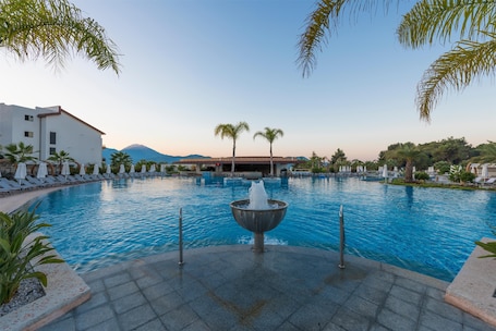 Una piscina techada, una piscina al aire libre, sombrillas