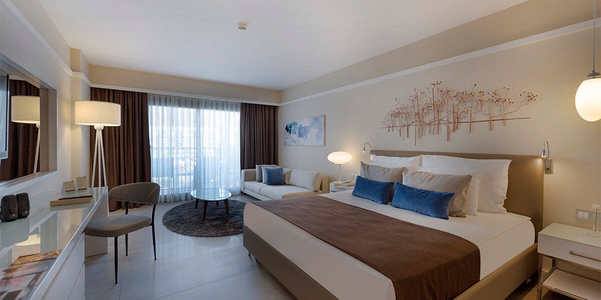 Una habitación de hotel con una cama, un escritorio, una silla, un sofá y una mesa de comedor.