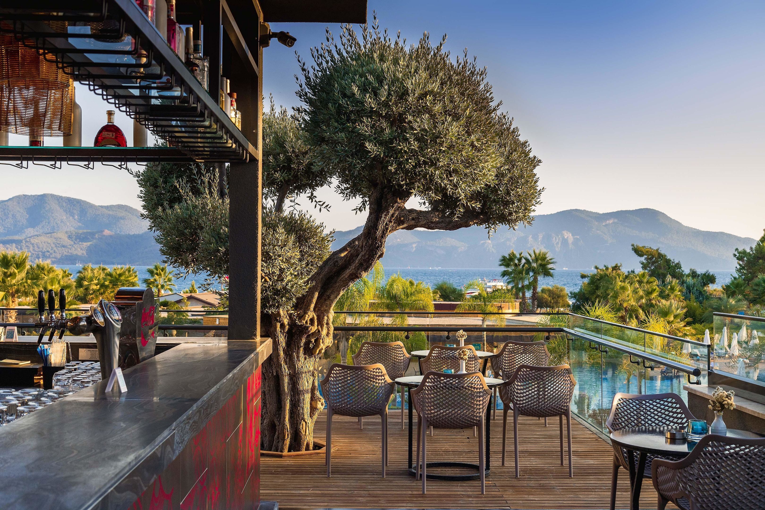 Espaço de bar com vista para montanhas, mesas ao ar livre e piscina.
