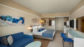 A modern hotel room with a bed, a sofa, a desk, and a TV.