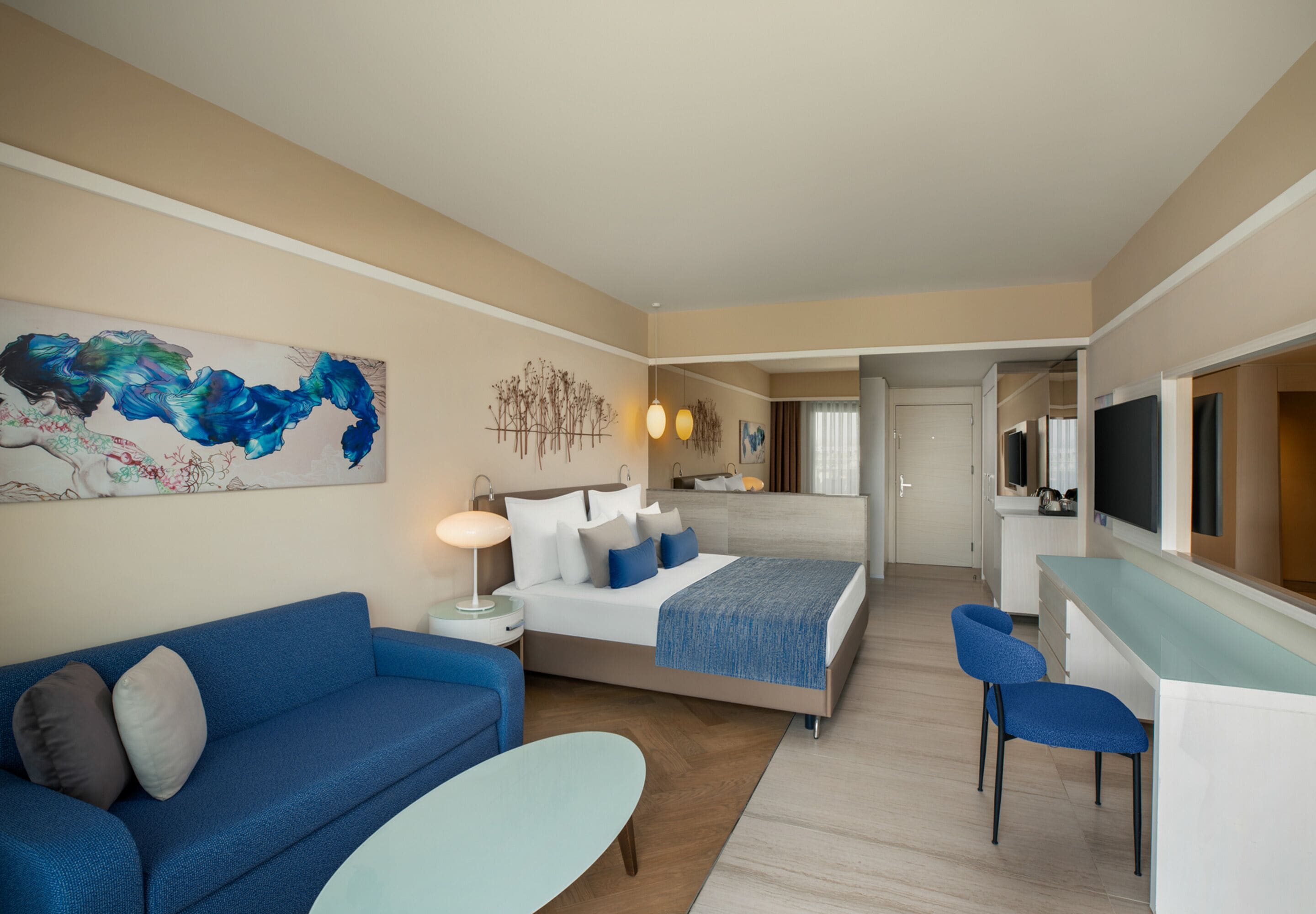 Una habitación de hotel moderna con cama, sofá, escritorio y televisor.