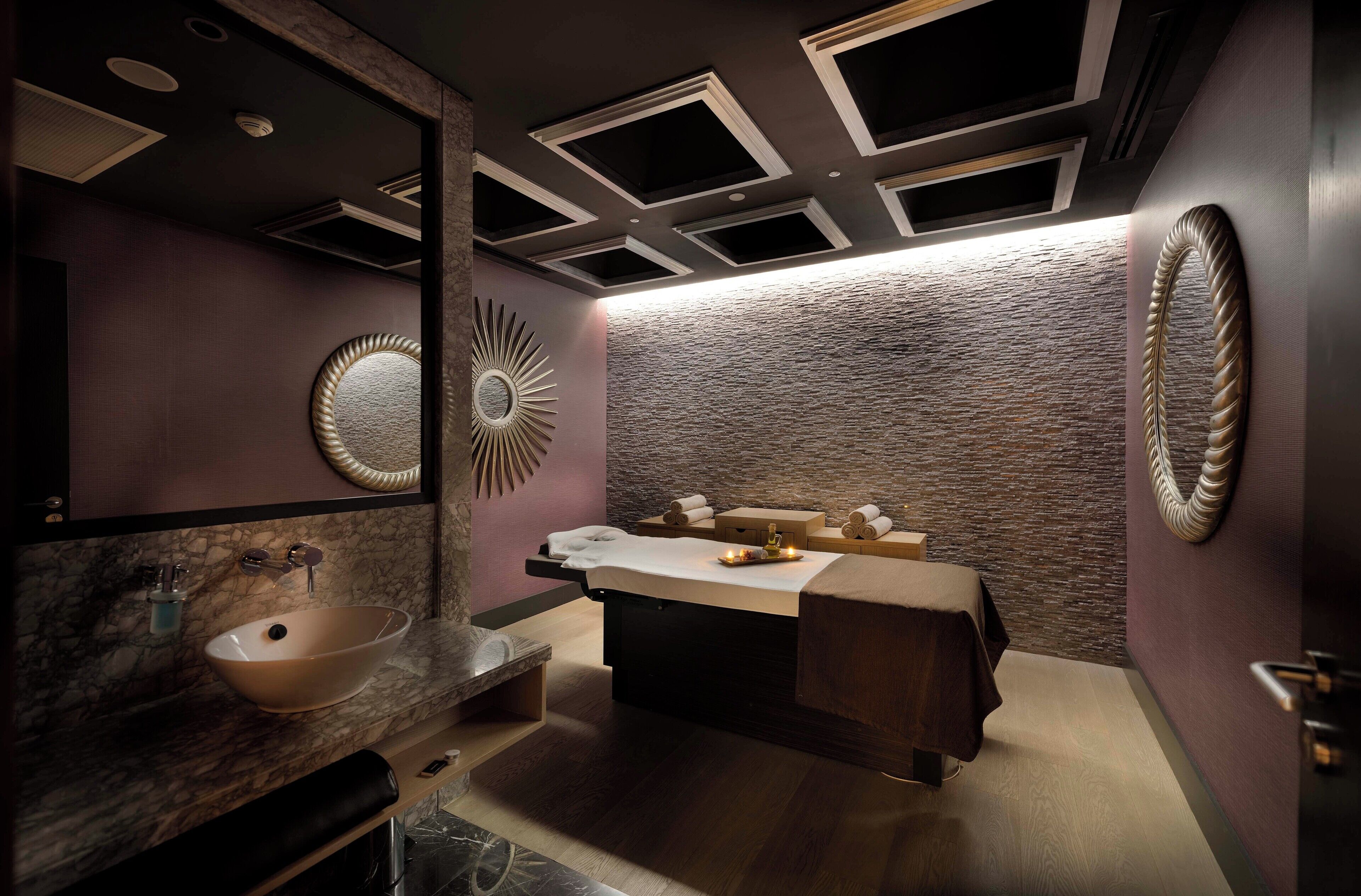 Une salle de bain moderne avec un lavabo en marbre, un grand miroir et un lit de spa.