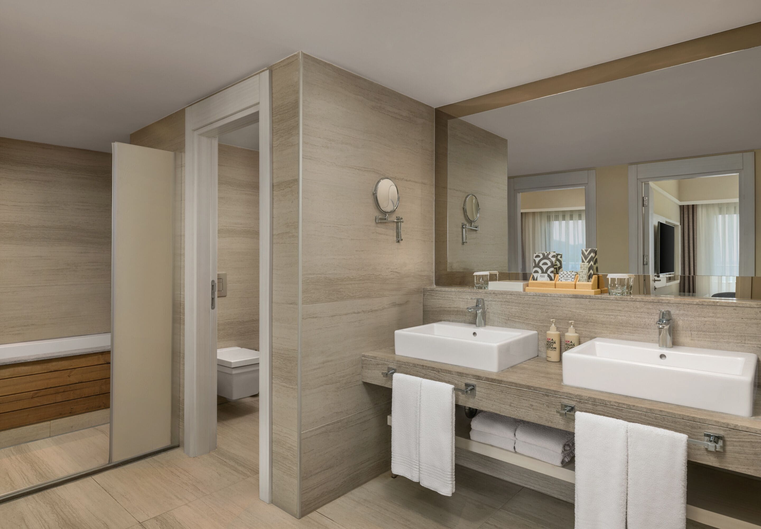 Une salle de bain moderne avec deux lavabos, un grand miroir et une douche à l’italienne.