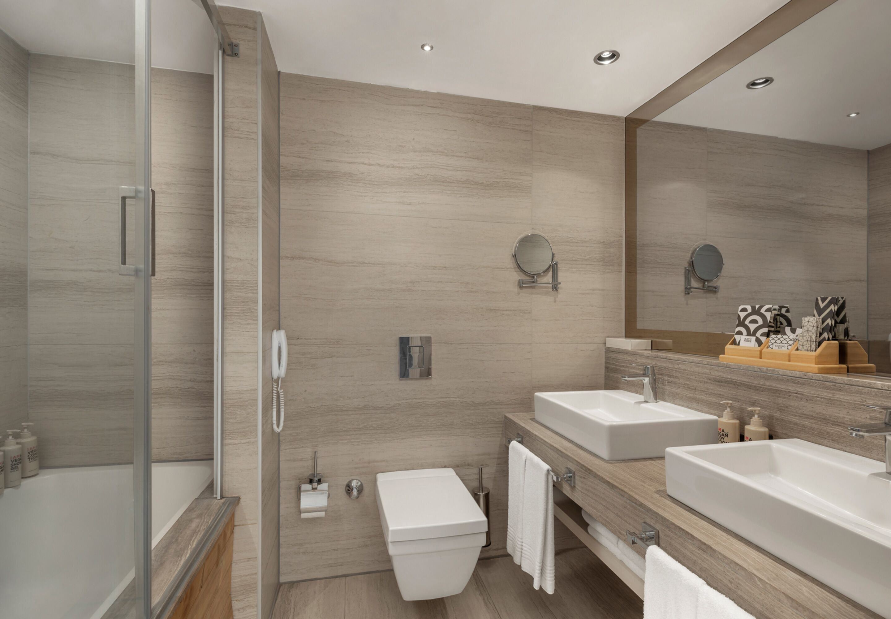 Un baño moderno con cabina de ducha de vidrio, tocador doble y retrete.