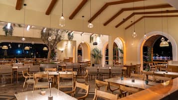 A restaurant with wooden tables and chairs, hanging pendant lights, and arched windows.