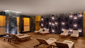 A spa room with wooden loungers, a glass partition, and wall-mounted lights.