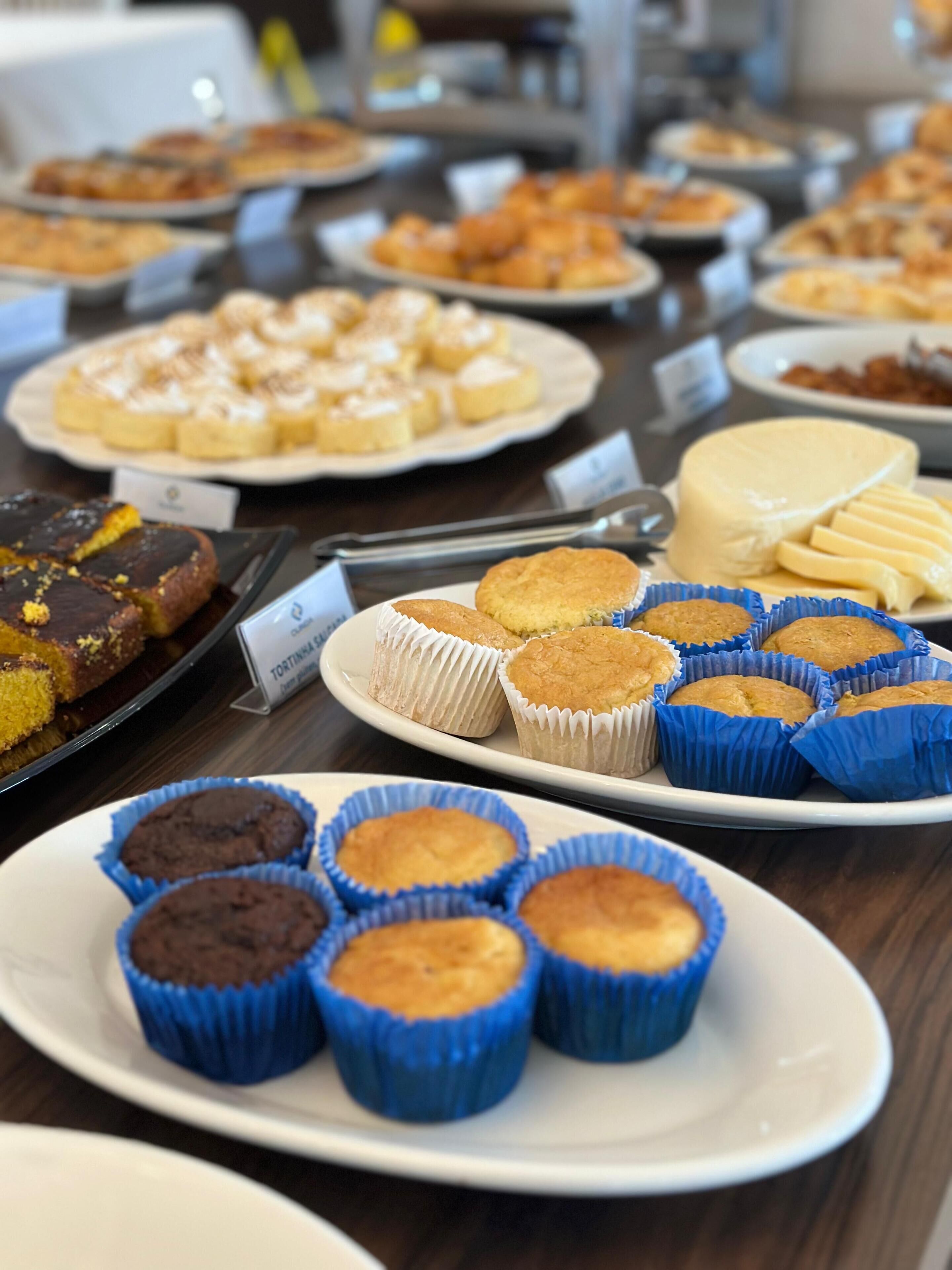 A buffet table with various baked goods, including muffins and pastries, arranged on plates.