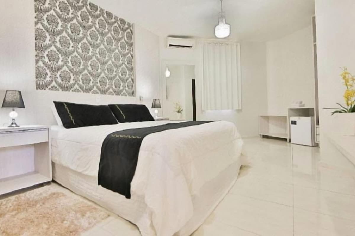Une chambre d’hôtel avec un lit, une table de chevet, une lampe et un mur décoré d’un motif.
