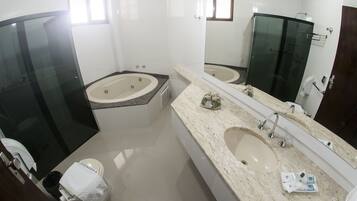 A modern bathroom with a glass-enclosed shower, a large bathtub, a vanity with a double sink, and a toilet.