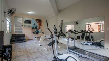 Un gimnasio con cintas de correr, elípticas y una banca para pesas.