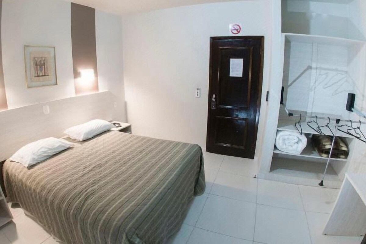 Une chambre d’hôtel comprenant un lit, des tables de chevet, une armoire et un miroir.
