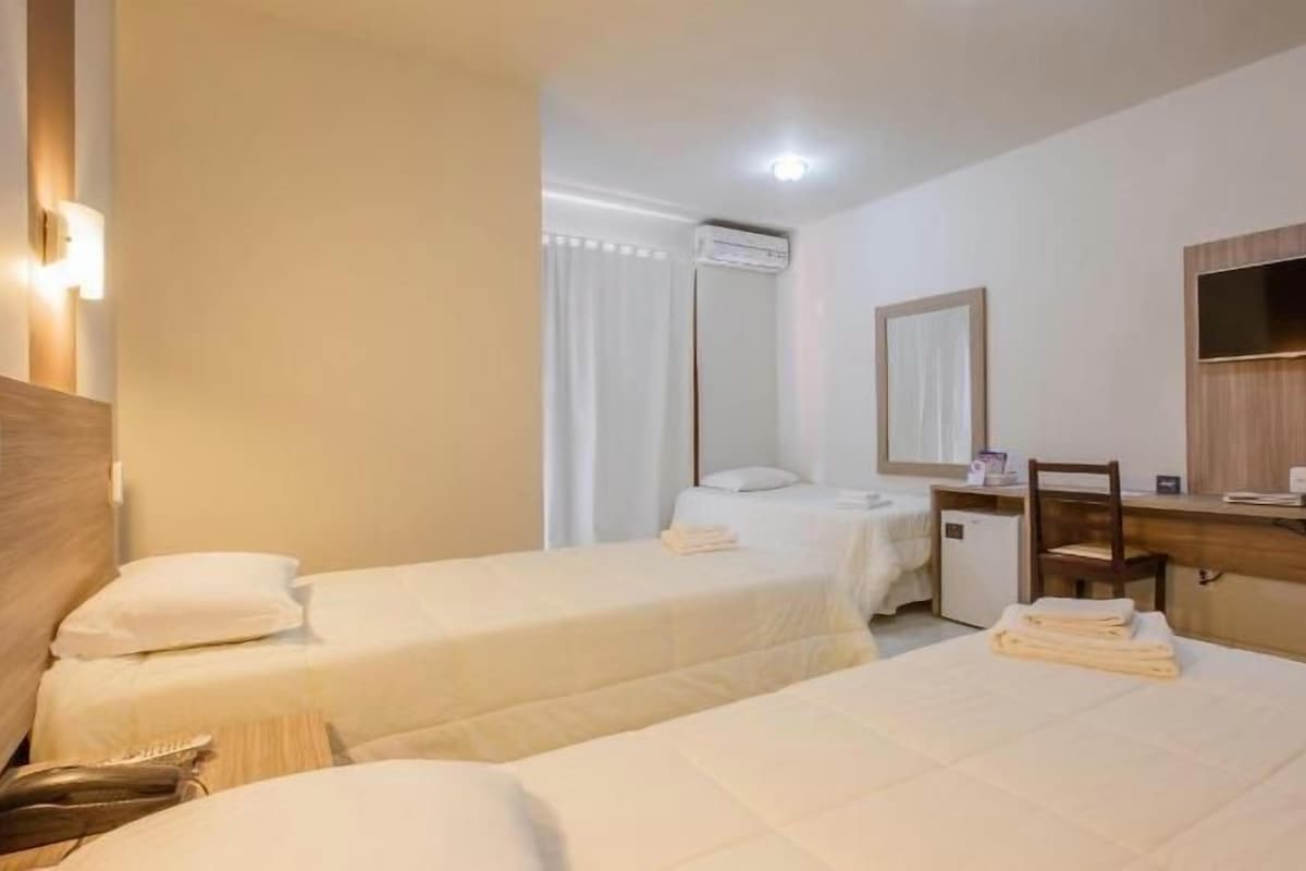 Une chambre d’hôtel avec deux lits, un bureau, une chaise, une télévision et un miroir.
