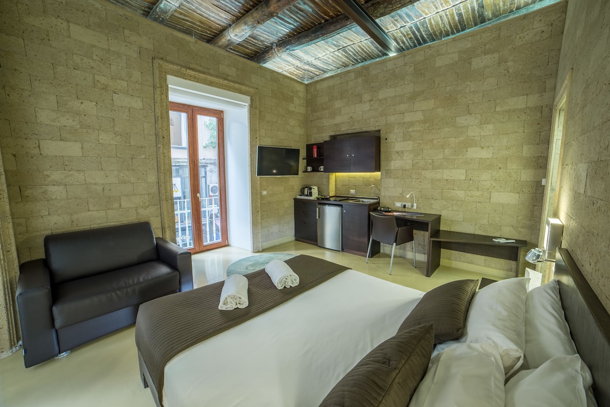Ein Hotelzimmer mit Bett, einer Sitzecke, einem Schreibtisch und einer Küchenzeile.