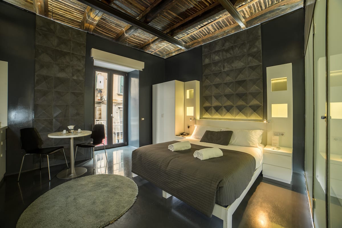 Ein modernes Hotelzimmer mit einem großen Bett, Nachttischen, einem runden Tisch und einem Sessel.