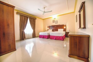 A hotel room with a large bed, a desk, a wardrobe, and a ceiling fan. - Frsan Plaza (Manama)