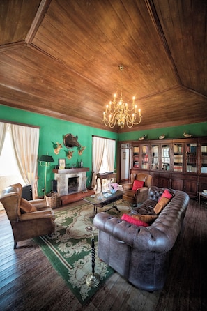 A cozy living room with a fireplace, leather furniture, and a bookshelf.