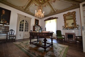 A room with a chandelier, a fireplace, a mirror, and a table with chairs.