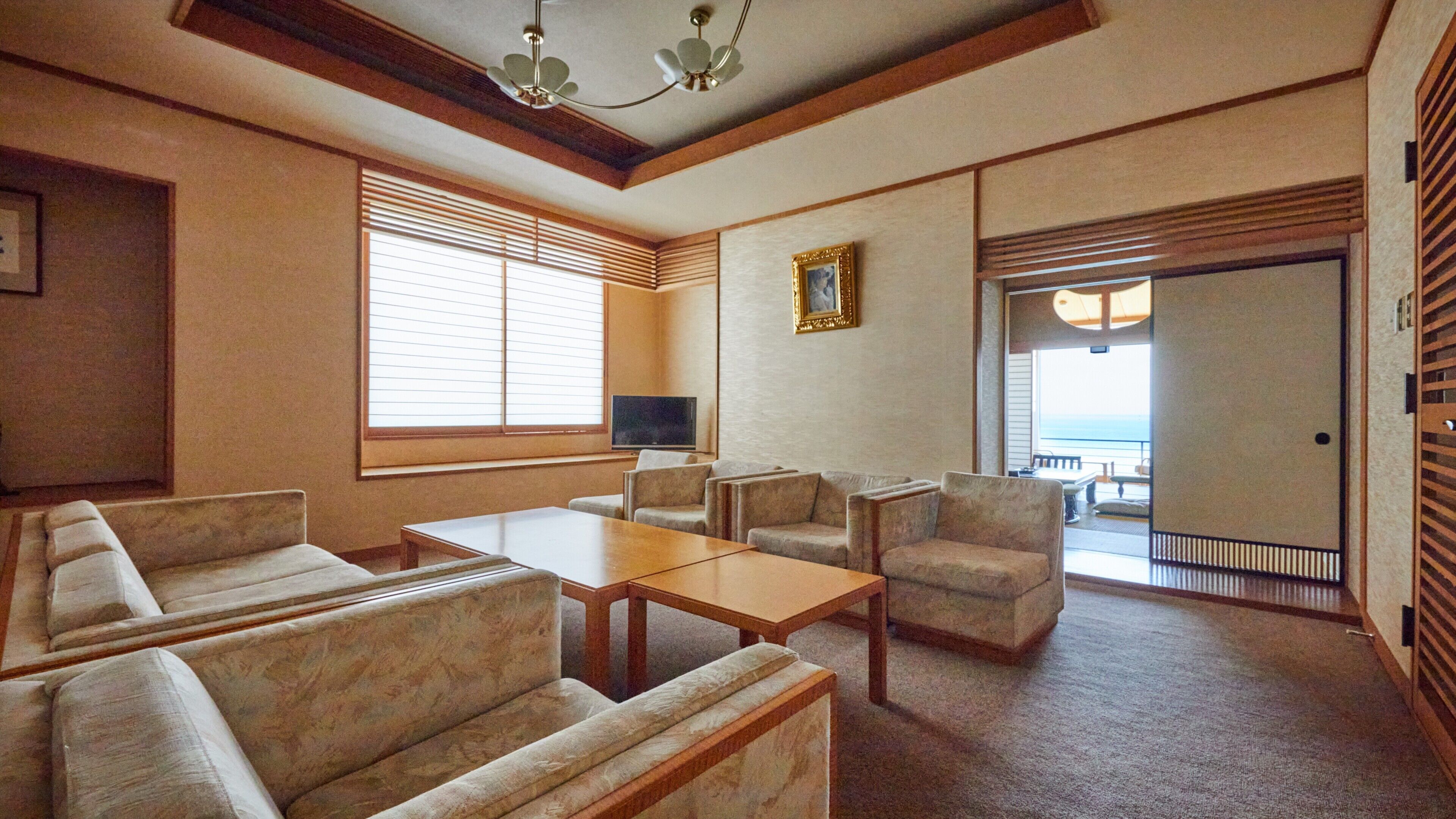 A hotel room with a sofa set, a coffee table, a TV, and a balcony with a view.