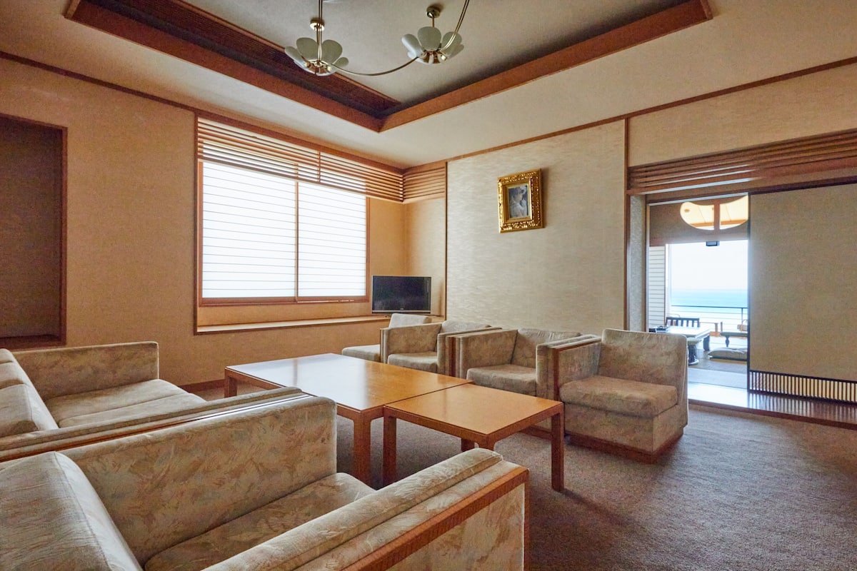 Habitación de hotel con sofá, mesa de centro, televisión y balcón con vistas.