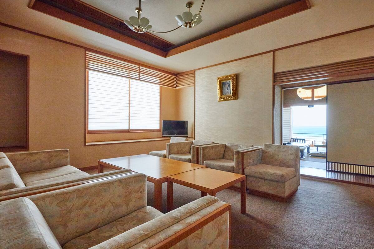 A hotel room with a sofa set, a coffee table, a TV, and a balcony with a view.