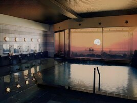 Una piscina interior moderna con vistas al atardecer a través de amplios ventanales.