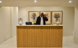 A reception desk with a wooden finish, two framed artworks on the wall, and two lantern-style lights on either side.