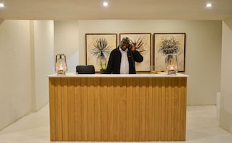 A reception desk with a wooden finish, two framed artworks on the wall, and two lantern-style lights on either side.