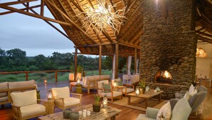 An outdoor seating area with stone walls, wooden furniture, and a fireplace.