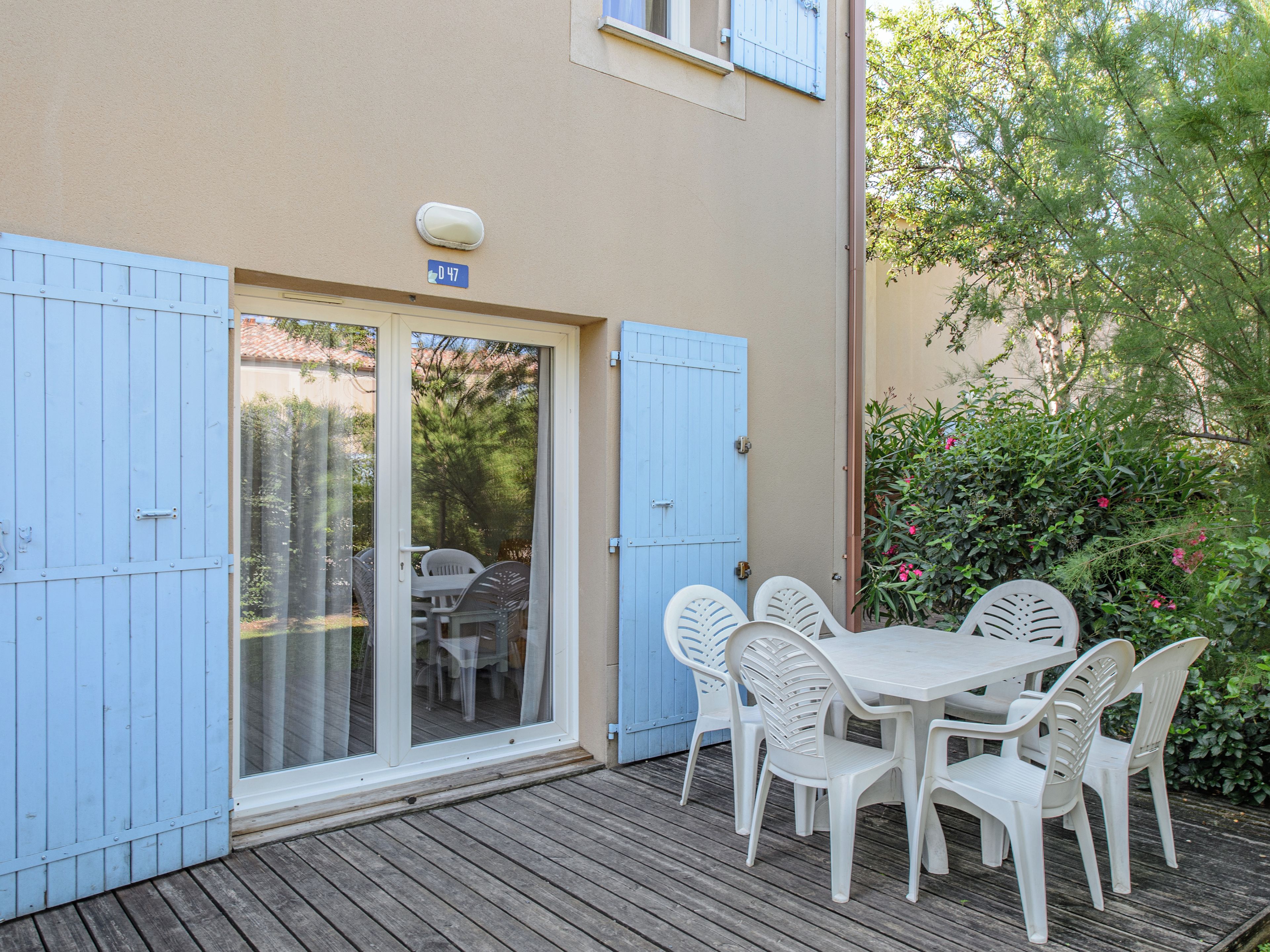 Une terrasse avec une table et des chaises, une porte-fenêtre coulissante et une porte bleue.