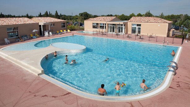 A swimming pool with multiple lanes, sun loungers, and a covered seating area.