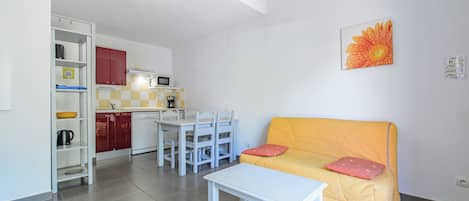 A compact living space with a kitchenette, a dining area, and a sofa.