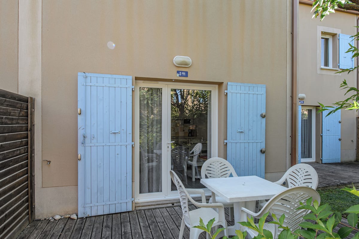 Un pati amb taula i cadires, una porta corredissa de vidre i una porta blava.