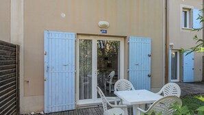 A patio with a table and chairs, a sliding glass door, and a blue door. - Les Demeures du Ventoux - Vacanceole (Aubignan)