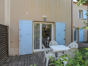 A patio with a table and chairs, a sliding glass door, and a blue door. - Les Demeures du Ventoux - Vacanceole (Aubignan)