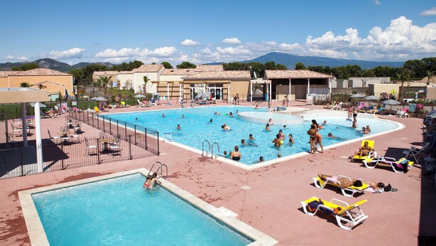 A large outdoor swimming pool with multiple lanes, surrounded by lounge chairs and umbrellas, set against a backdrop of mountains and clear skies. - Les Demeures du Ventoux - Vacanceole (Aubignan)