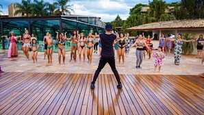 A group of people dancing on a wooden deck with a glass building in the background.