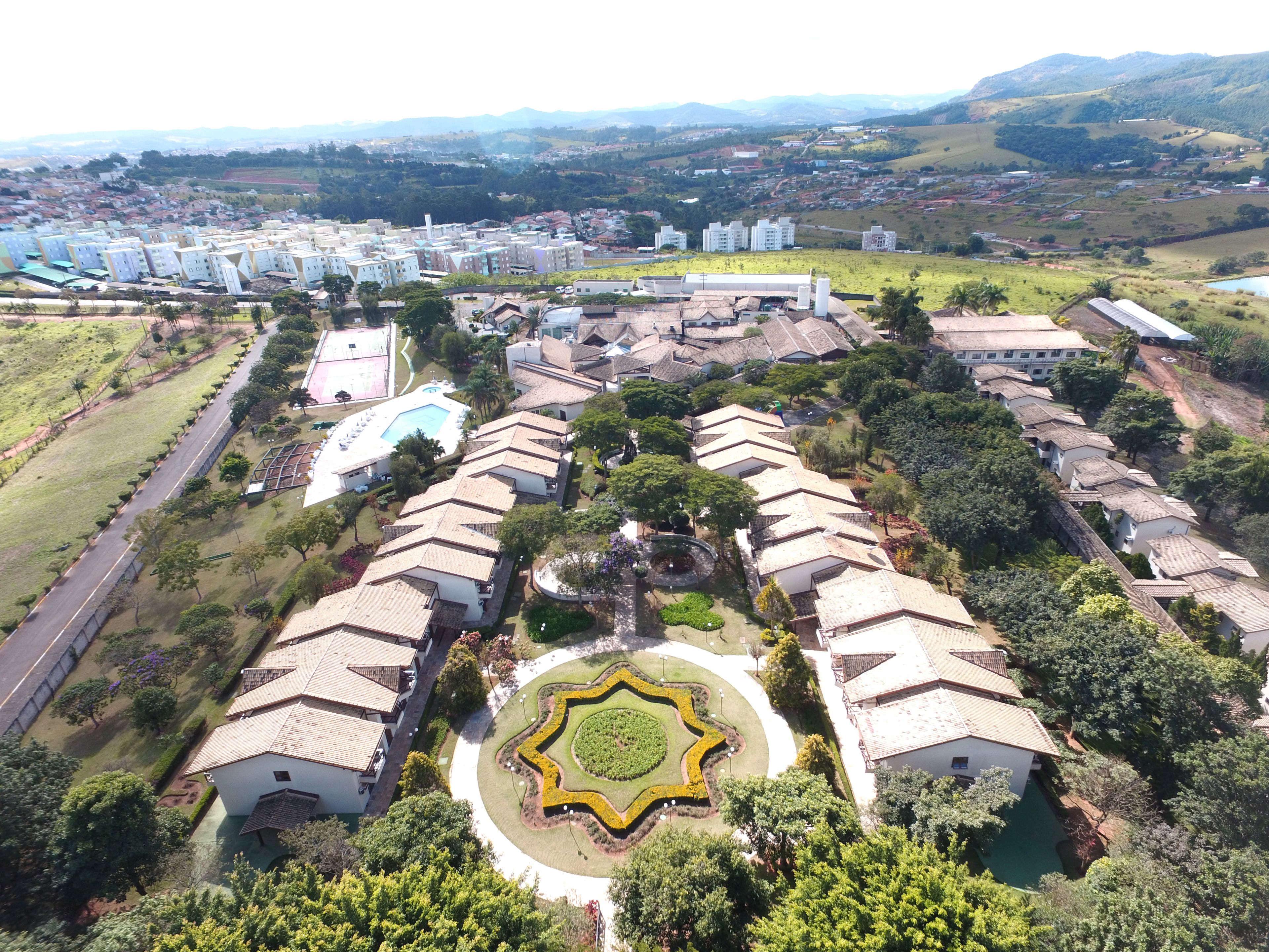 Vista aérea de um bairro residencial com várias casas, um jardim central e uma piscina.