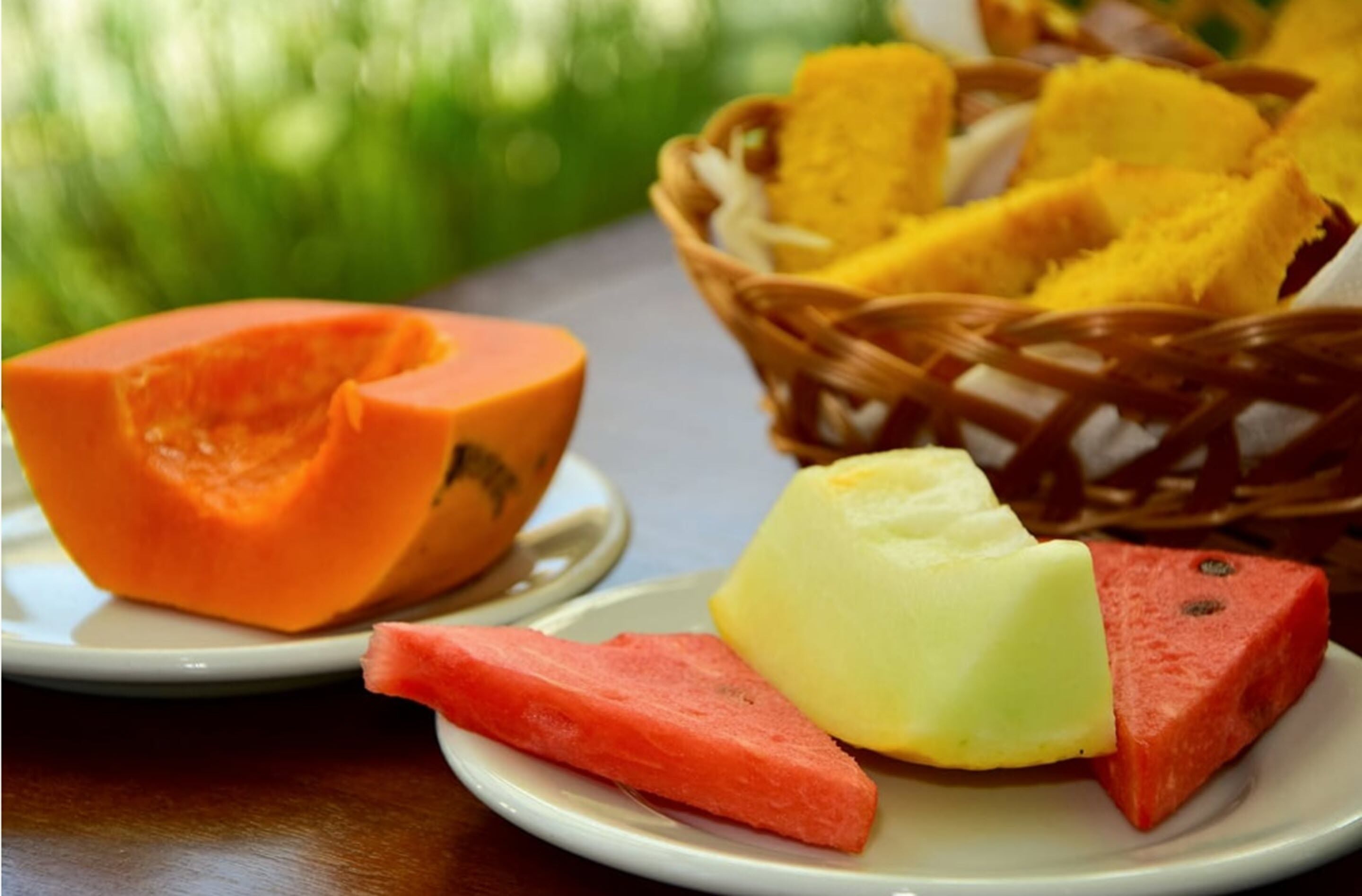 Um prato com metade de mamão papaia, uma fatia de melancia e uma fatia de abacaxi.